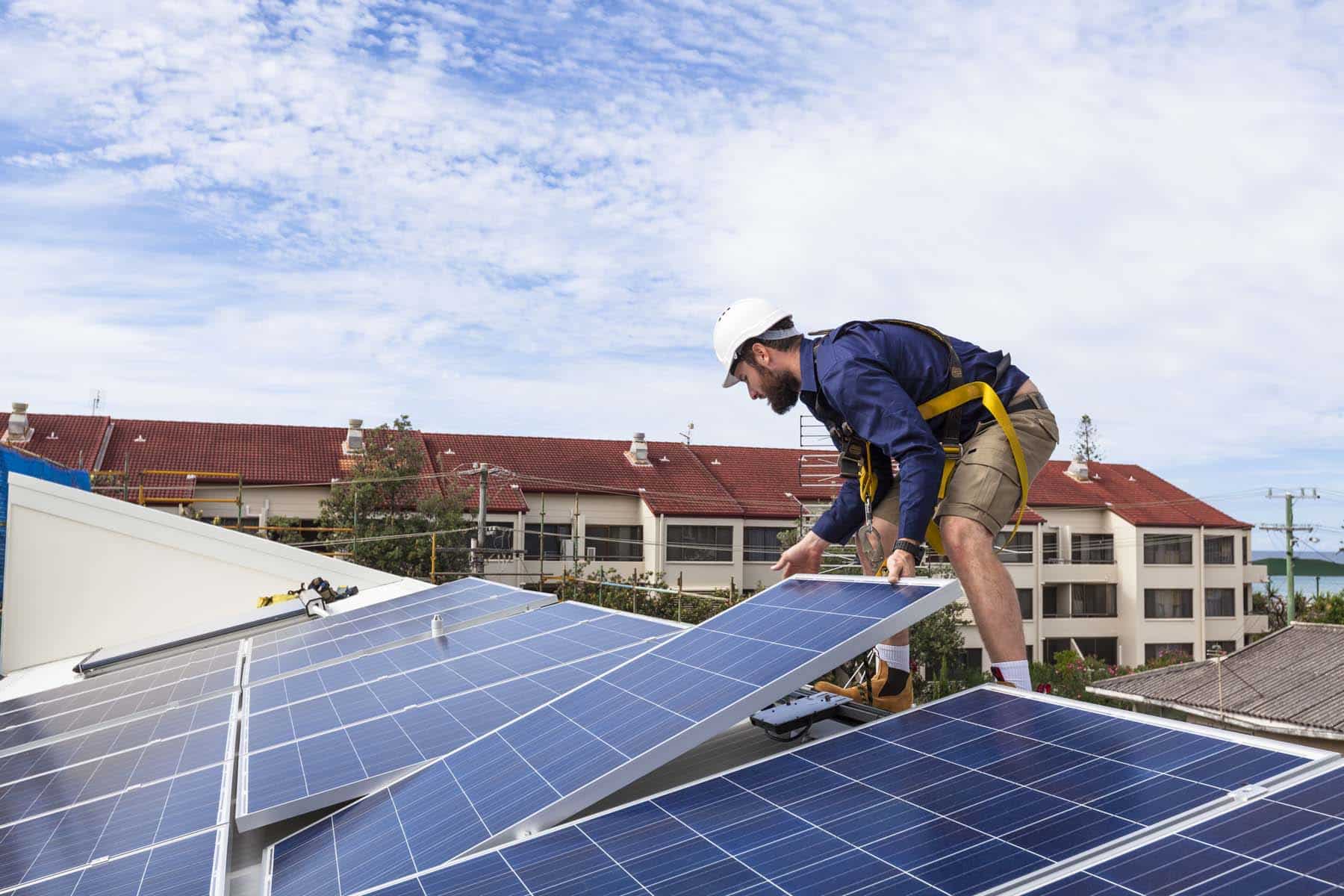 Solar panel technician installing solar panels on roof